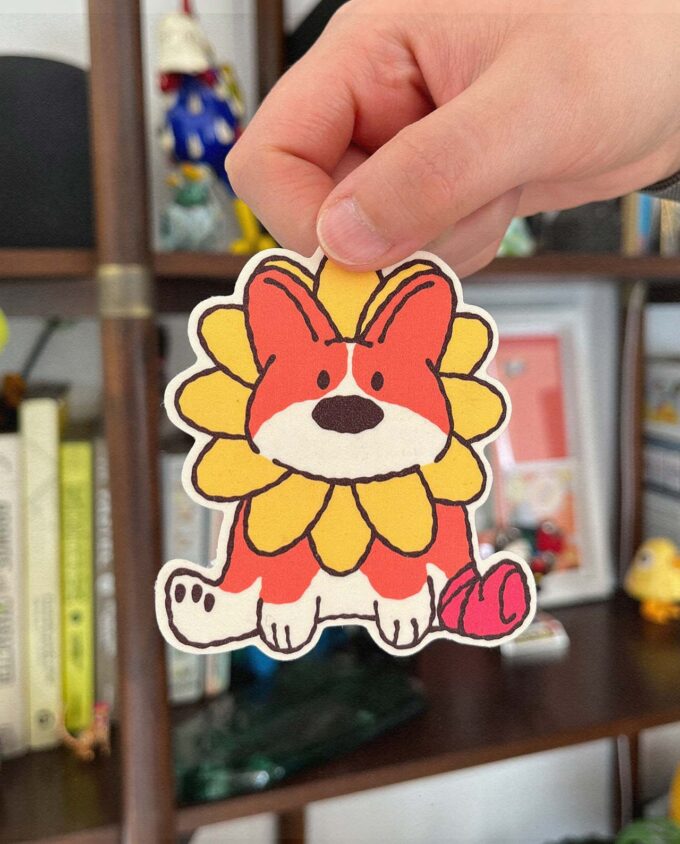 sticker de una Ilustración de un perro corgi sentado con una flor amarilla alrededor de su cuello