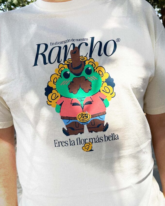 Detalle de una playera con una ilustración de una rana ranchera con un ramo de flores amarillas