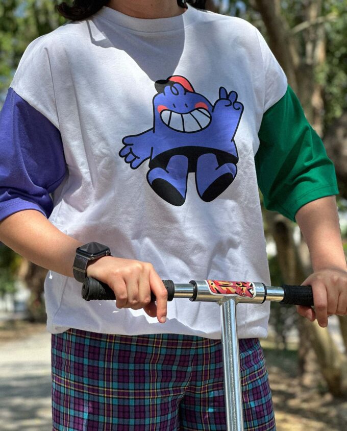 Playera de algodón con ilustración en serigrafía, mangas morada y verde, en un scooter