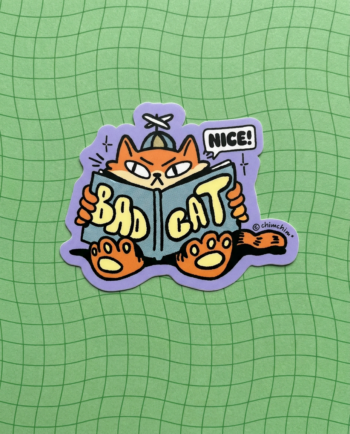 Sticker vinil matte Bad Cat 9x7 cm, gato naranja con gorra leyendo libro de cómo ser un gato malo, contorno recortado ChimChim México